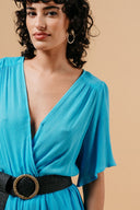 blauwe-massika-jumpsuit-met-kruishals-elastische-tailleband-korte-mouwen-grace-and-mila-model-close-up-vooraanzicht-1