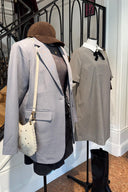 Twee etalagepoppen met de nieuwste herfstmode van Sienna voor een binnentrap. Links: een casual-chique look met een grijze blazer, donkere top, zwarte spijkerrok en een bruine pet. Rechts: een klassieke geruite jurk met een witte kraag en zwarte strik, gestyled met een donkerbruine tas en hoge zwarte laarzen.