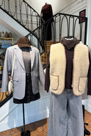 Detail van twee gestylede etalagepoppen bij Sienna. Links: een outfit met een grijze blazer, zwarte rok, bruine corduroy pet en een lichte crossbodytas. Rechts: een herfstachtige look met een zachte, beige teddy bodywarmer gedragen over een donkerbruine trui met col en een bijpassende sjaal, gecombineerd met wijde grijze jeans.